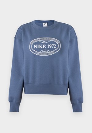 Μπλε φούτερ Nike με μακριά μανίκια, ριμπ μανσέτες και τελείωμα, με λευκό κείμενο "NIKE 1972" και λογότυπο σε οβάλ στο στήθος.