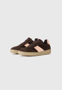 Brune semskede sneakers med en rosa teksturert stripe, rund tå og en lys brun gummisåle. Har snøring og polstret krage.