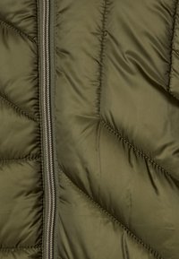 Oliwkowa kurtka puchowa z ukośnym pikowaniem, zamek błyskawiczny z przodu z kontrastowym stębnowaniem oraz gładką, błyszczącą teksturą materiału.