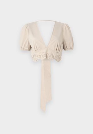 Top court beige avec des manches bouffantes, décolleté en V profond et bordure décorative en œillets à l'ourlet. Comprend une ceinture en tissu nouée. Texture lisse.