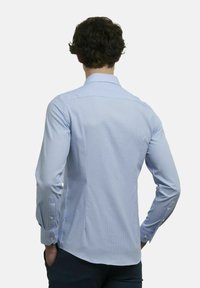 Lichtblauw langemouwen shirt met een klein ruitpatroon, knoopsluiting bij de kraag en knopen op de manchetten, gezien vanuit de achterkant. Soepele textuur.