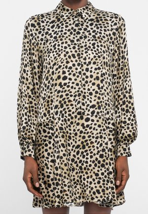 Robe à manches longues avec imprimé léopard beige et noir, col boutonné, et jupe ample légèrement évasée.