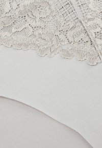 Underkläder med spetsdetaljer i ljusgrått med en mjuk textur, med delikata blommönster längs midjebandet.