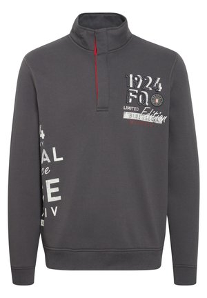 Sivý pulóver so zipsom do polovice goliera. Obsahuje červené akcenty, vyšívaný text a rôzne grafiky na prednej strane. Materiál z mixu bavlny.