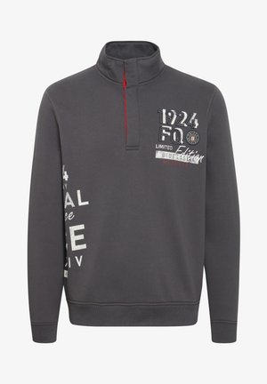 Grå genser med halv-zip krage. Har røde detaljer, broderte tekster og forskjellige grafikker på forsiden. Laget av en bomullsblanding.