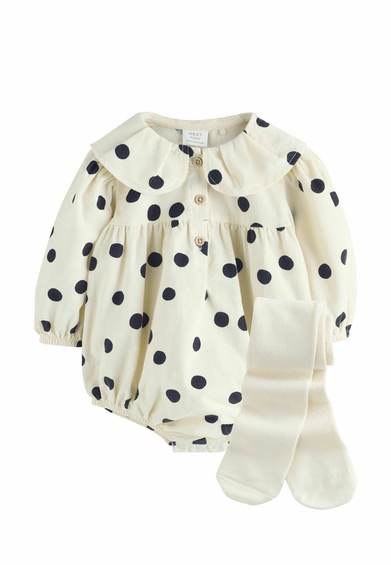 Krēmkrāsas bodijs ar baltām punktiņām, lielu apkakli, koka pogām un elastīgām aprocēm, kopā ar atbilstošām krēmkrāsas zeķītēm.
