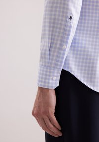 Lichtblauw geruit shirt met knoopmanchetten, een subtiele geborduurde detail op de mouw, en een gladde katoenstructuur.