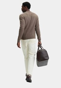 Brun ribbet sweater, hvide bukser og mørke lædersko. Bærer en mørk lædertaske med en struktureret form og metalbeslag.