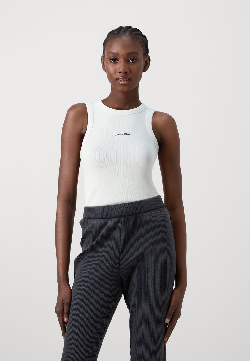 Bílý žebrovaný tílko s kulatým výstřihem, na přední straně je černý nápis "Předpokládám, že ano...". Spárováno s tmavě šedými žebrovanými kalhotami.