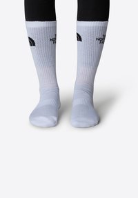 Calcetines blancos con diseño acanalado y logo negro en la parte superior. Fabricados con una mezcla de materiales, cuentan con una suela acolchada y puntera reforzada.