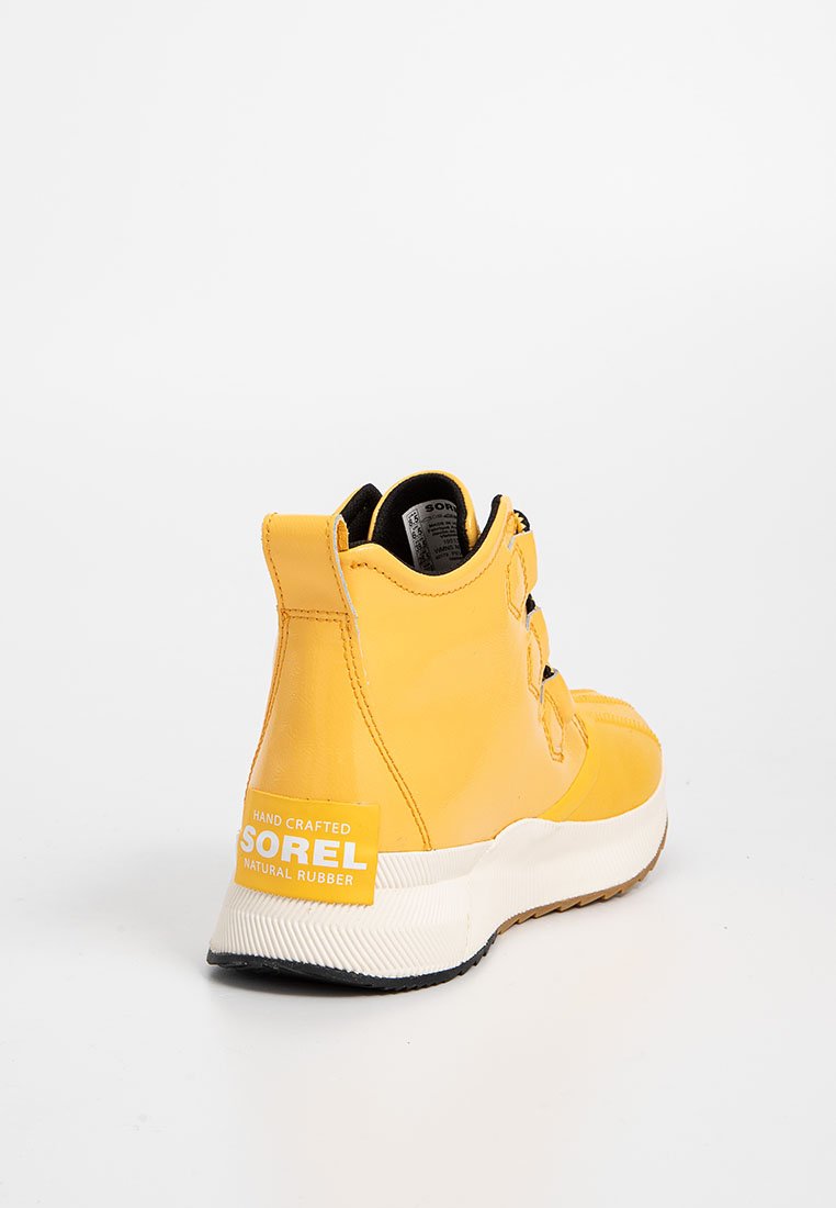 Żółty kauczukowy but za kostkę z teksturowanym wykończeniem, wyposażony w czarne akcesoria, wyściełany kołnierz oraz biały akcent na pięcie z logo.