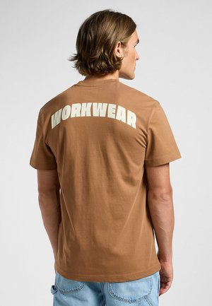 T-shirt in cotone marrone con grande scritta bianca "WORKWEAR" sulla schiena. Vestibilità classica con maniche corte e collo tondo.