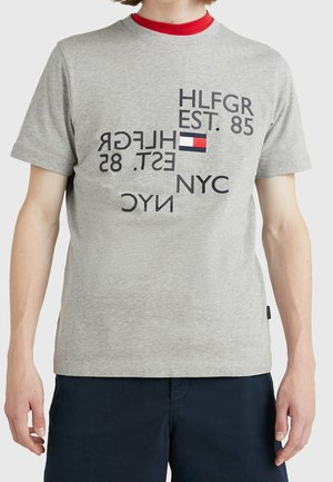 Graues Baumwoll-T-Shirt mit einem grafischen Design aus verschiedenen Textformen, darunter "HLFGR EST. 85" und ein kleines Logo mit roten und blauen Akzenten.