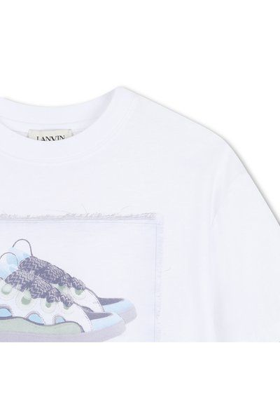 Λευκή μπλούζα με στρογγυλή λαιμόκοψη και ραμμένο κέντημα που απεικονίζει ένα ζευγάρι αφηρημένα πολυχρωματικά αθλητικά παπούτσια σε παστέλ αποχρώσεις.