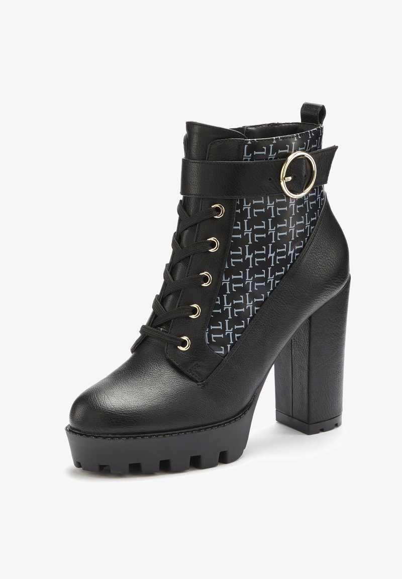 Bottine noire à talons avec une finition en cuir texturé, présentant un panneau à motifs, des accents en métal doré et une semelle épaisse à profil cranté.