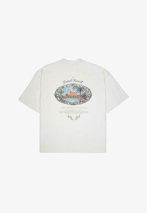 T-shirt bianco a maniche corte con una grafica colorata che rappresenta una scena di un resort con palme, contornata in nero, accompagnata da testo decorativo sotto.