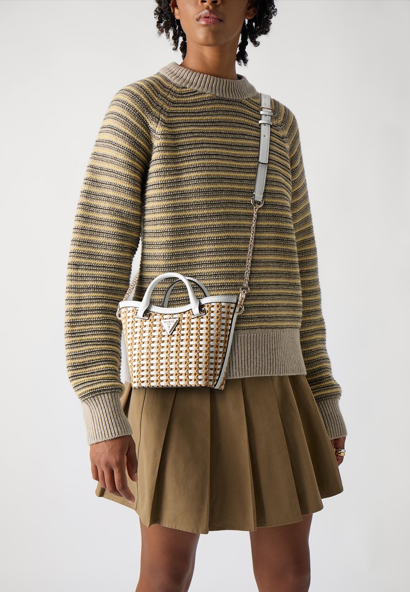 Maglione a righe in beige, verde e grigio abbinato a una gonna plissè oliva. Piccola borsa intrecciata in bianco e beige con tracolla a catena.