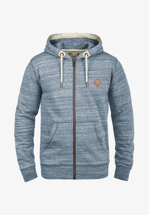 Haut de hoodies zippé bleu clair en tissu doux, avec un motif texturé, des cordons de serrage et un accent en cuir en forme de diamant sur la poitrine.
