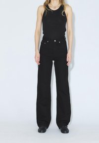 Jeans de mezclilla negros de talle alto con pierna recta, con detalles de botones de cobre, un diseño clásico de cinco bolsillos y una textura suave.