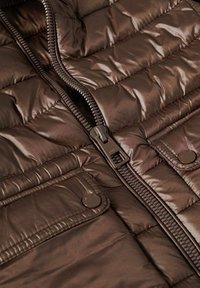 Brown padded vest showing quilted design with a front zipper and snap button closures. Features a smooth, shiny texture.
