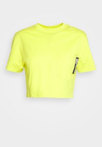 Avklippt t-shirt i klart neongul bomull, med en bröstficka och en etikettaccent på sidan. Enkel design med rund hals.