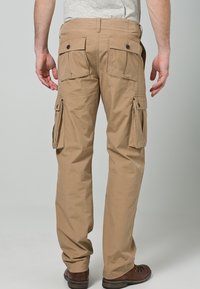 Beige cargobroek met een rechte pijp, voorzien van meerdere zijzakken, knoopsluitingen en een lichtgewicht katoenen stof.
