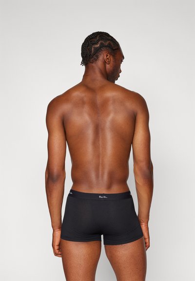 Caleçons boxers noirs en tissu lisse avec une taille flexible arborant un logo de marque, vus de dos sur une personne.