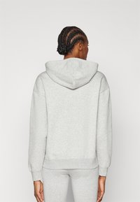 Grå, överdimensionerad hoodie i mjukt tyg med en rymlig huva, neddragna axlar och ribbade ärmslut. Minimalistisk design, inga synliga mönster.