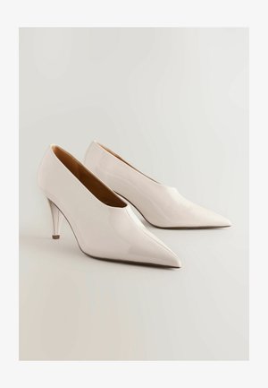Chaussures à talons aiguilles blanches brillantes avec un bout pointu et un talon slim. Surface lisse et design minimaliste.