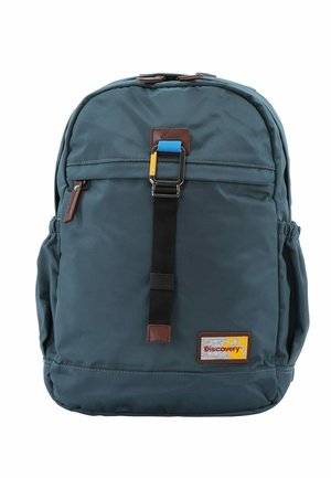 Backpack in dark teal fabric with brown accents, featuring a main compartment, front zip pocket, side pockets, and a colorful buckle.