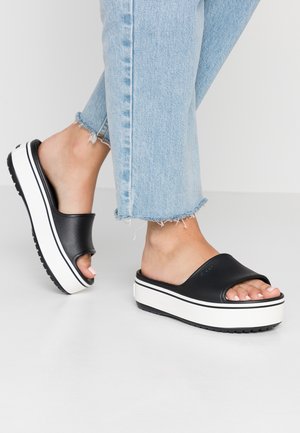 Czarne klapki na platformie z otwartym noskiem, wykonane z gładkiego materiału, z białą teksturowaną podeszwą i czarnymi paskami akcentującymi.