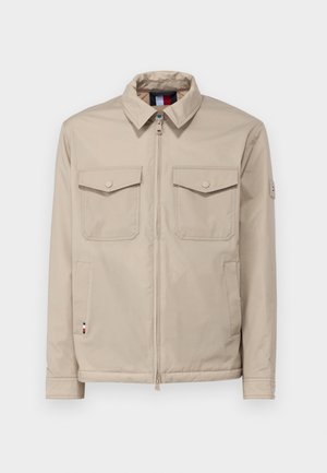 Beige Jacke mit Reißverschluss vorne, zwei knöpfbaren Brusttaschen, seitlichen Taschen und einem Kragen. Mit einem Logo-Highlight am Ärmel. Glatte Textur.