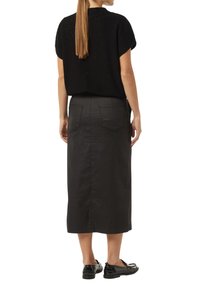 Schwarzes Strickoberteil mit kurzen Ärmeln und rundem Ausschnitt, kombiniert mit einem schwarzen Jeans-Midirock mit aufgesetzten Taschen hinten und gerader Schnittform.