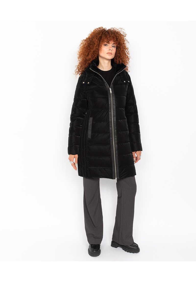 Abrigo acolchado negro con cierre de cremallera, cuello alto y bolsillos laterales. Presenta un material brillante, un ajuste relajado y detalles contrastantes en gris.