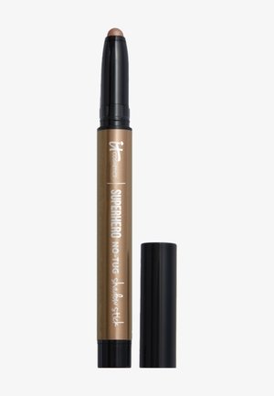 Barras de sombra de ojos en tono bronce, con base y tapa negras, etiquetadas como "Superhero No-Tug Shadow Stick" de IT Cosmetics.
