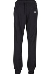 Svarte joggebukser laget av bomullsblandingsstoff, med elastisk midjebånd, mansjetter på bena og en baklomme med logoetikett.