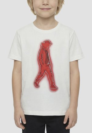 Kind draagt een wit T-shirt met een rood silhouet van een lopend persoon met pet en casual kleding gedrukt op de voorkant.