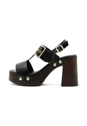 Sandale à plateforme en cuir noir avec talon bloc épais marron, boucles dorées et clous métalliques sur les brides, bout ouvert et design avec bride arrière.
