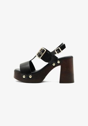 Sandale à plateforme en cuir noir avec talon bloc épais marron, boucles dorées et clous métalliques sur les brides, bout ouvert et design avec bride arrière.