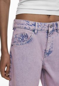 Jeans de mezclilla color púrpura claro con un patrón deslavado, que cuentan con un bolsillo frontal con un logotipo en relieve y un diseño tradicional de cinco bolsillos.