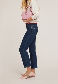 Vaqueros de tiro alto azul oscuro con corte recto, combinados con zapatos rosa de tacón bajo con herrajes dorados y un bolso rosa claro.