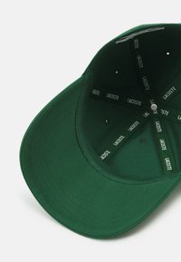 Grønn baseballcaps med en strukturert design. Innvendig har den merkelapper og ventilasjonshull. Laget av teksturert stoff.