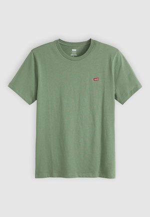 Zelena pamučna majica s kratkim rukavima, okruglim izrezom i malim crvenim Levi’s logom na lijevoj strani prsnog dijela. Glatka tekstura.