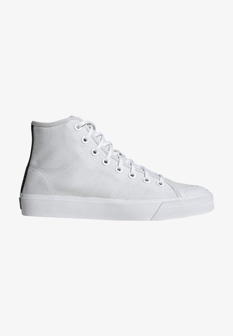 Zapatillas de caña alta en lona blanca, con suela de goma, seis ojetes y paneles laterales texturizados con finas rayas.