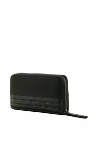 Portefeuille noir avec une partie supérieure en tissu et une partie inférieure en cuir texturé, fermeture éclair, profil fin, et une dragonne pour une manipulation aisée.