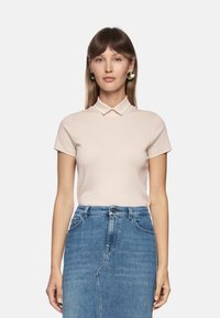 Pale pink polo shirt with short sleeves and a collar, paired with a blue denim A-line skirt featuring front pockets and a button closure.