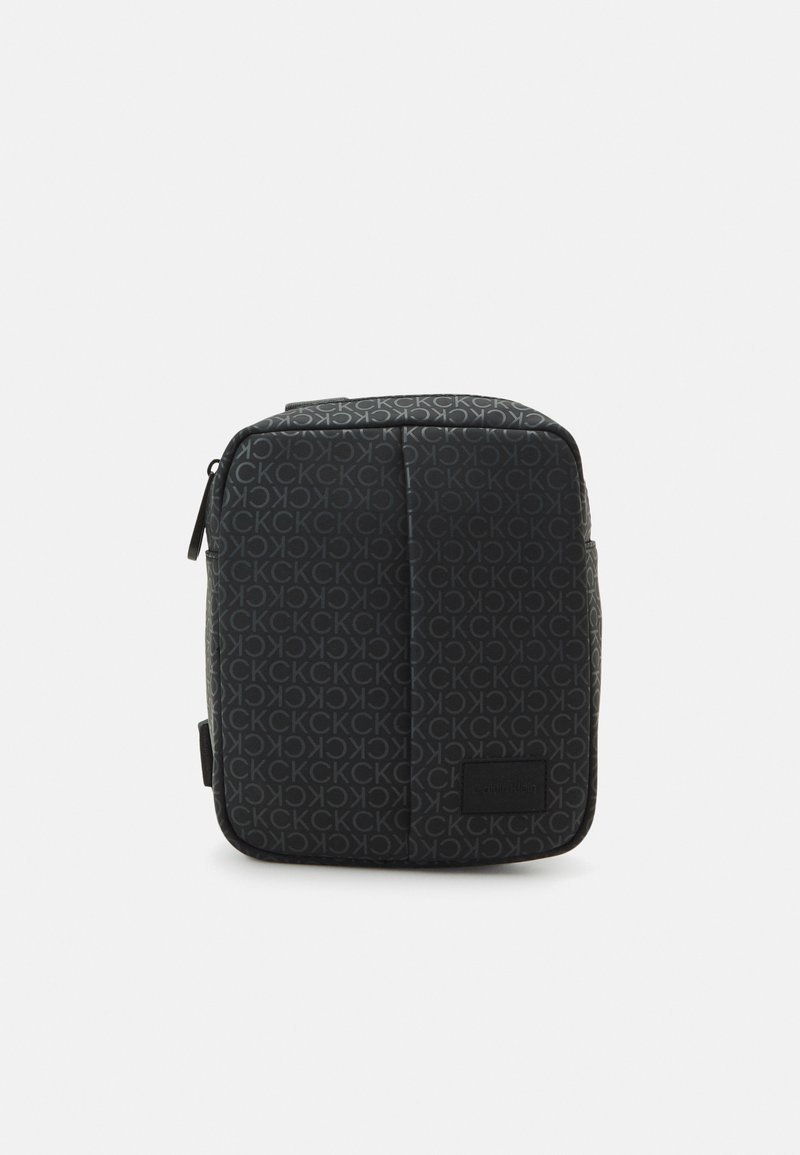 Zaino nero con un motivo a logo ripetuto. Realizzato in materiale liscio e resistente, presenta una chiusura con zip e una tasca frontale.