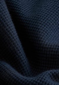 Tissu bleu marine texturé avec un motif en grille, présentant une surface douce et tissée qui semble épaisse et confortable.