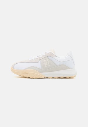 Scarpe sportive bianche realizzate con un mix di materiali in mesh e suede. Presentano un accento beige, punta arrotondata e una suola in gomma testurizzata.