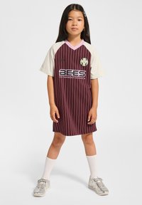 Bordeaux vertikalt stribet jerseykjole med korte cremede ærmer, lyserød krave, logo og teksten "BEES INTERNATIONAL", båret med sølvfarvede sneakers og hvide sokker.